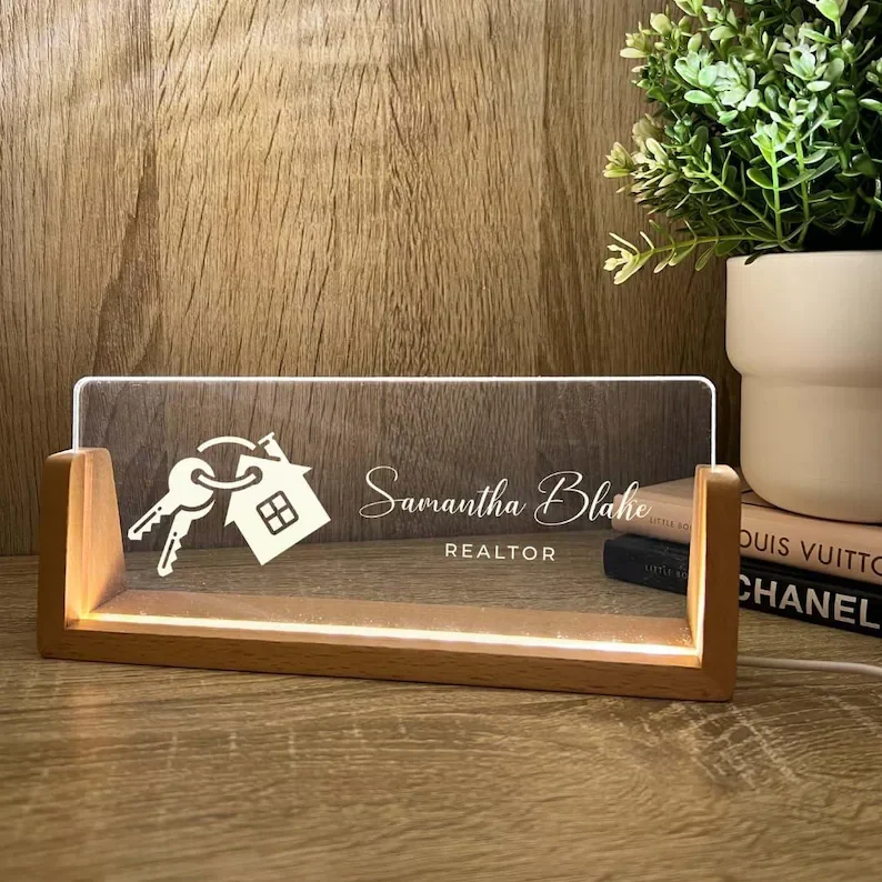 A clear desk name plate on a wooden desk.