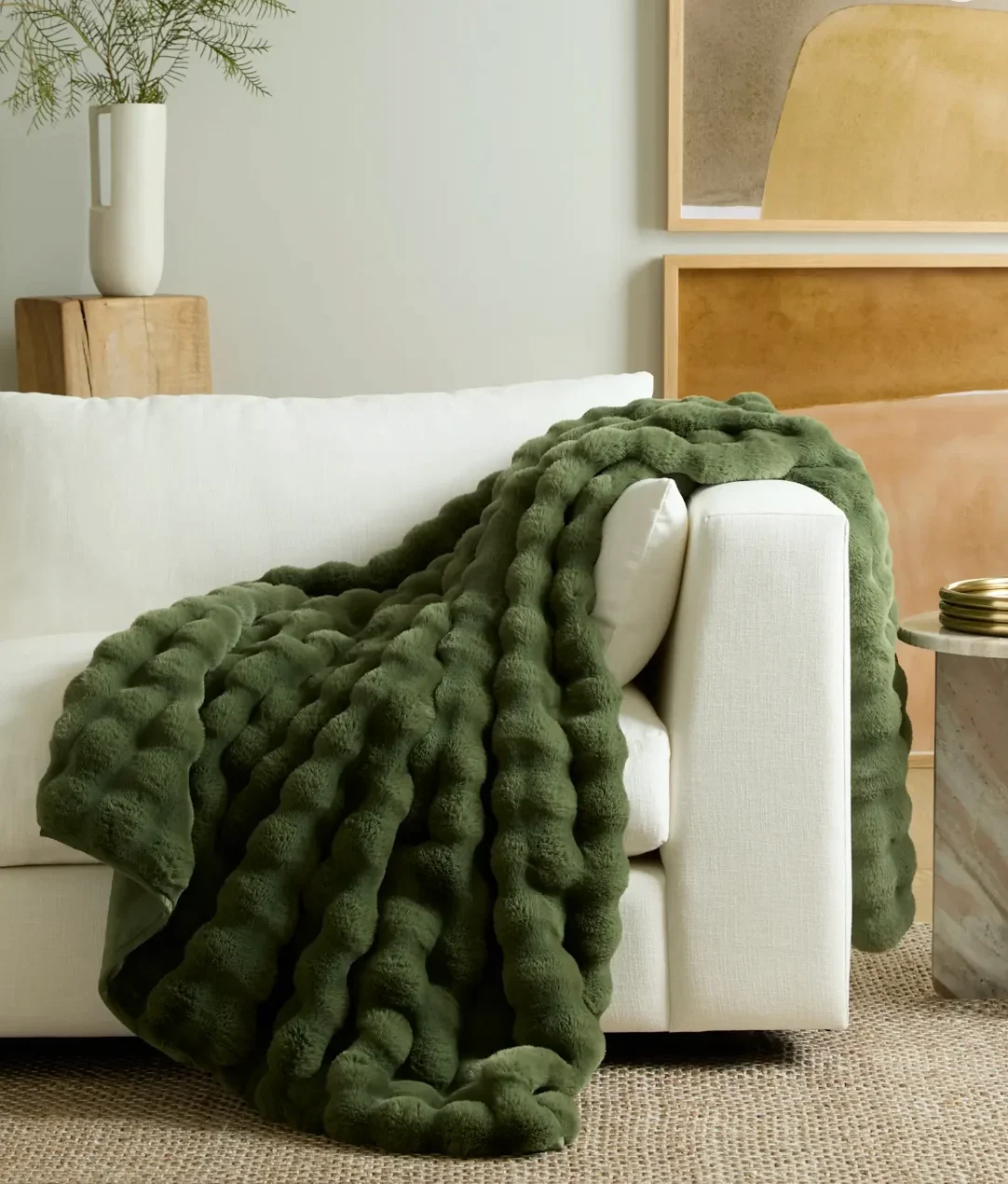 A green plush throw thrown over a white sofa.