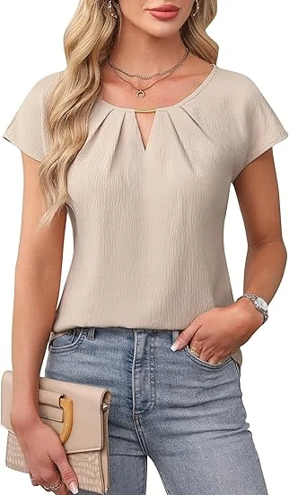 A woman wearing a beige blouse over jeans holding a beige purse.