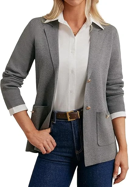 A woman wearing a gray cardigan over a white blouse and blue jeans.