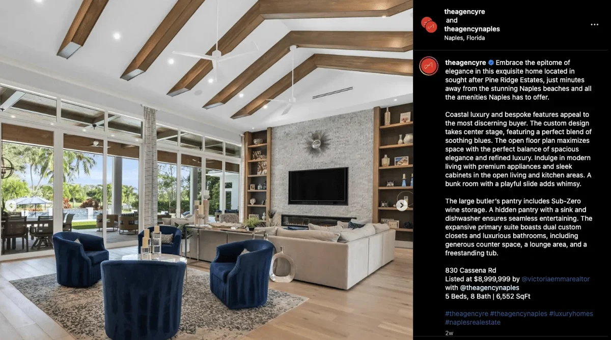 Screenshot of a large living space with a wrap-around sofa, a separate seating area, and floor-to-ceiling windows overlooking a deck with palm trees.