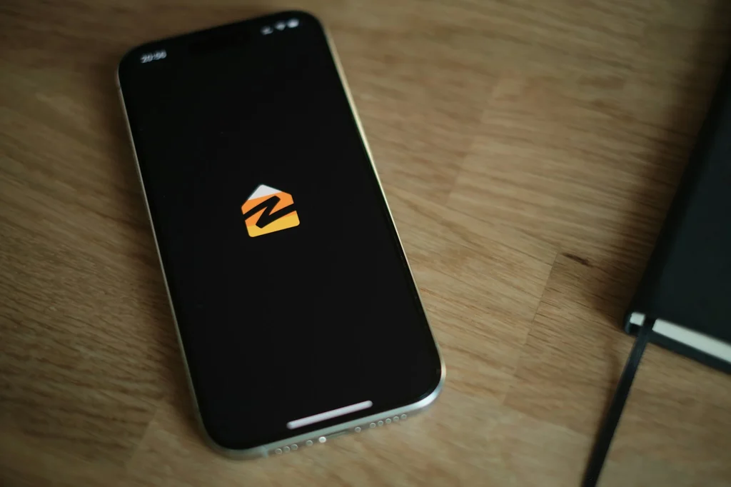 Zillow app logo displayed on a smartphone resting on a wooden desk
