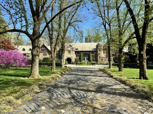 The exterior castle style home, with trees in front of the property, and a stone driveway leading to the front door.