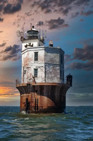 Lighthouse with sunset behind it, alone in the ocean.